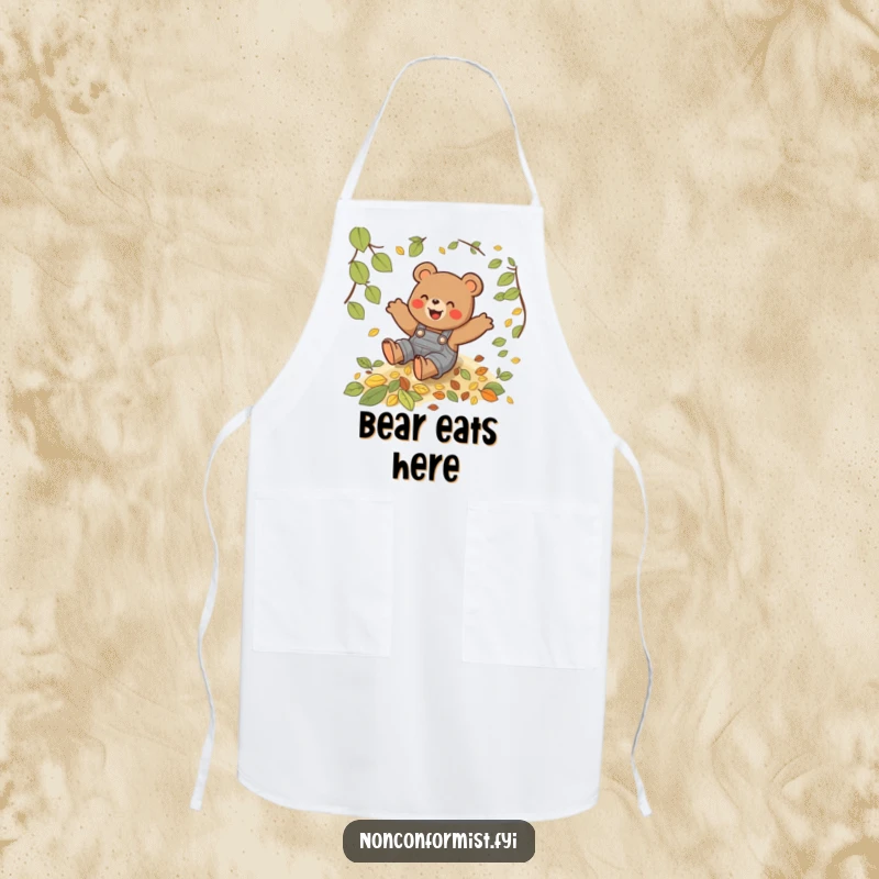 Funny apron featuring a playful bear in overalls sliding down a hill of leaves while cooking.