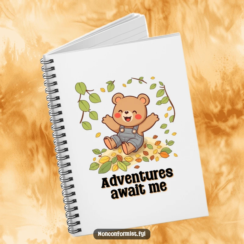Funny notebook with a playful bear in overalls sliding down a hill of leaves, perfect for fall journaling.