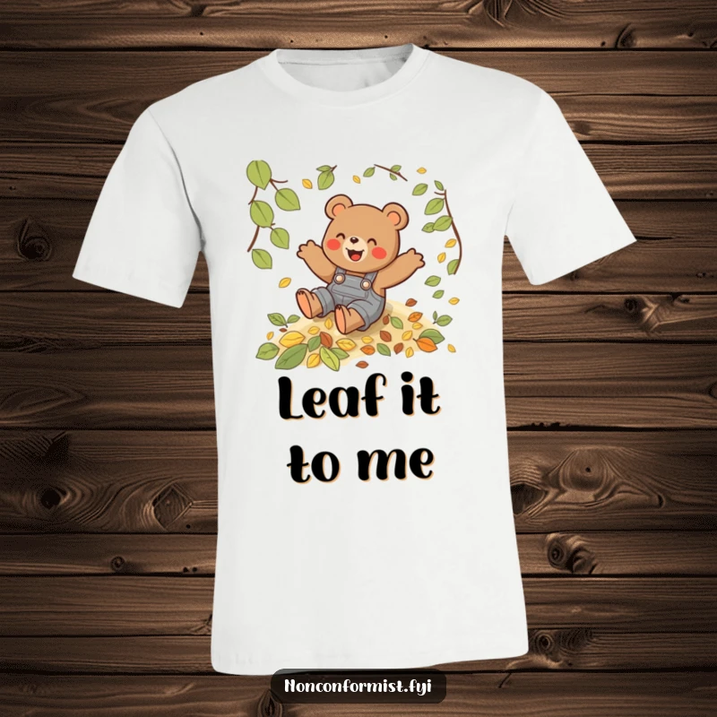 Funny T-shirt with a playful bear wearing overalls, joyfully sliding down a steep hill covered in colorful autumn leaves.